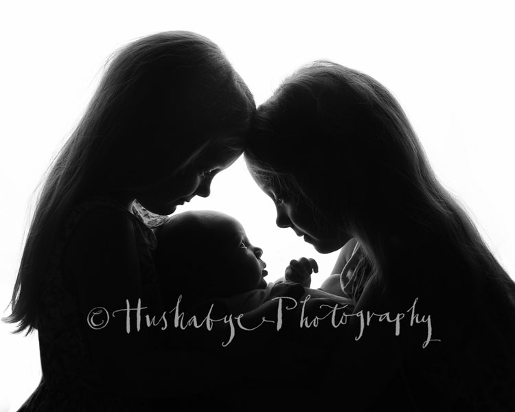 Silhouette of two sisters holding their baby sisters, London, Tunbridge Wells, Sevenoaks, Tonbridge, Kent, bespoke newborn photography